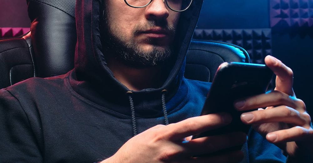 A Man in Black Hoodie Sweater Using His Mobile Phone