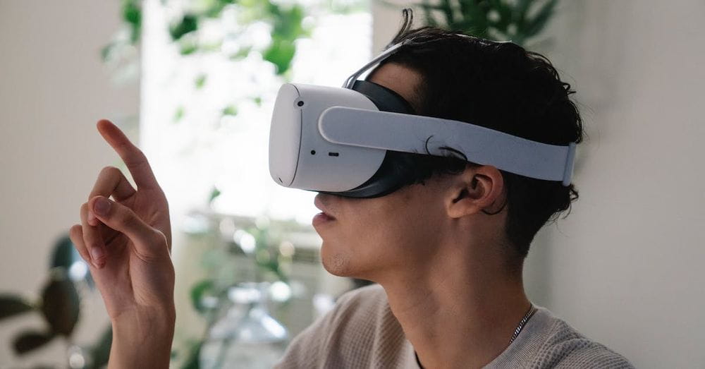 Side view of concentrated young guy in casual clothes experiencing virtual reality in modern headset at home