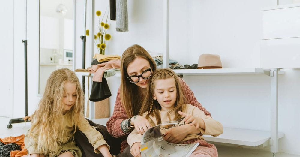 Woman with Two Girls Browsing Magazines on the Floor