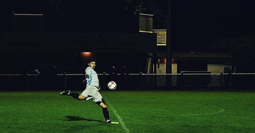 Person Kicks Soccer Ball in Field